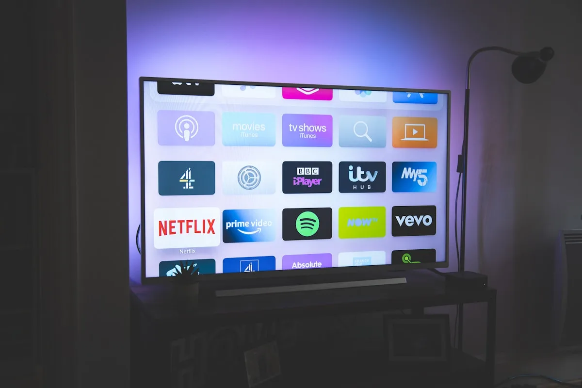 Smart TV com luz de fundo roxa e azul refletindo na parede da sala