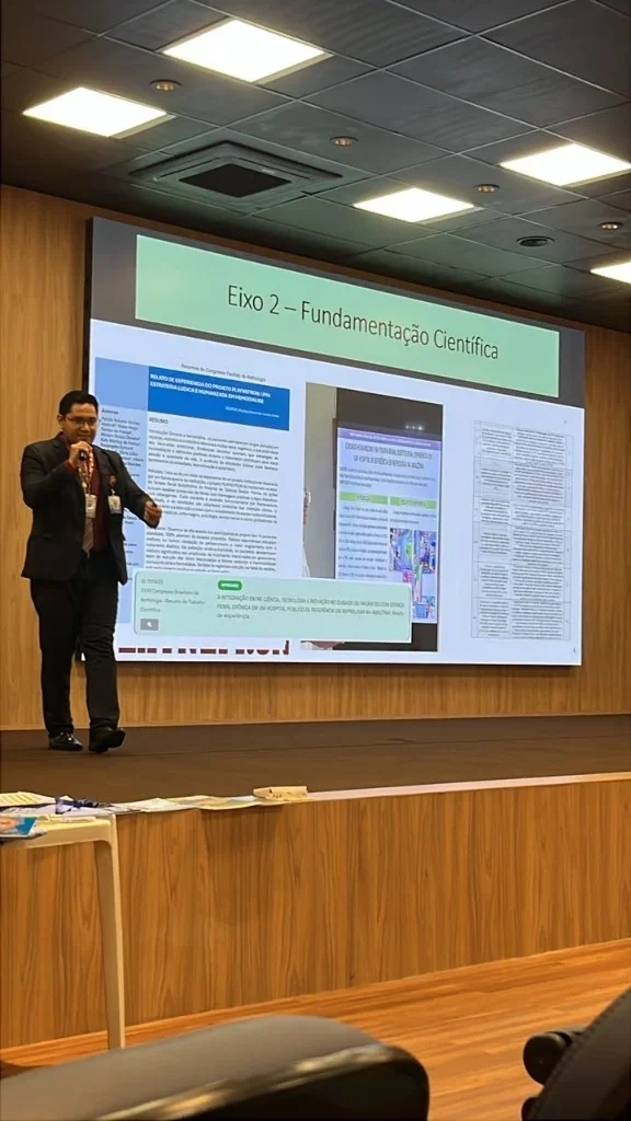 Patrick Abdoral no palco com projeção do slide Eixo 2 — Fundamentação Científica exibindo publicações e artigos