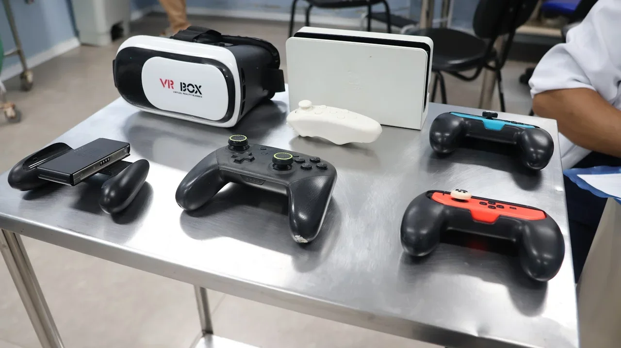 Bancada cirúrgica auxiliar com console Nintendo Switch, controles Joy-Con com grips ergonômicos e headset VR Box