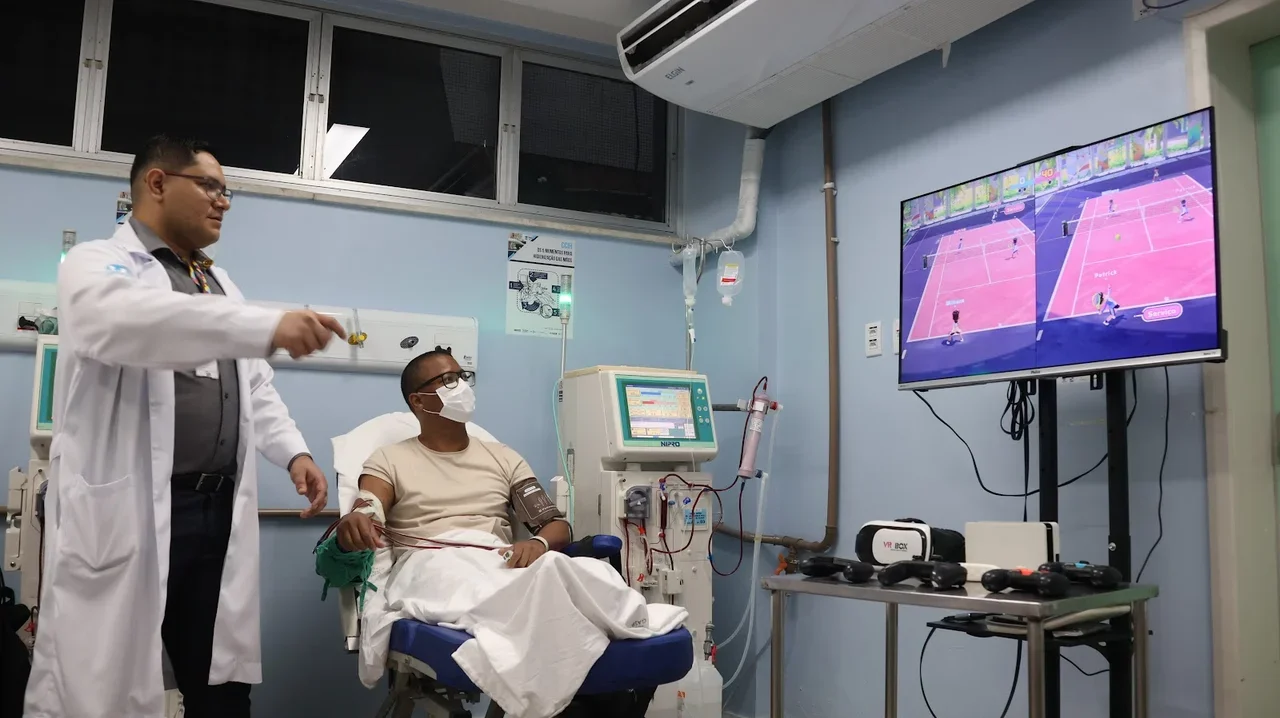Tela de Smart TV com partida dividida de Nintendo Switch Sports Tennis disputada por paciente em hemodiálise