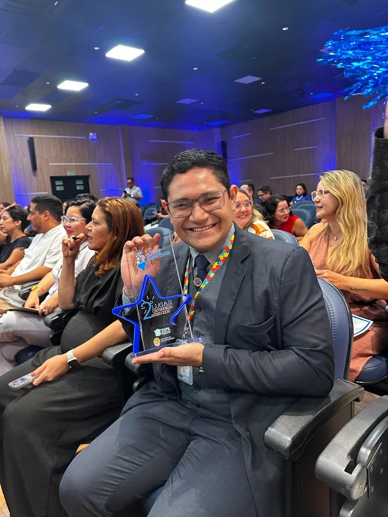 Patrick Abdoral sorridente segurando o troféu de 2º lugar na Categoria Serviços do Prêmio Inova Servidor