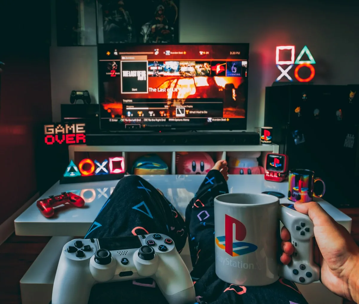 Setup pronto pra sessão de GTA Online Sala de jogos com controle PlayStation, caneca temática e menu de troféus na TV ao fundo