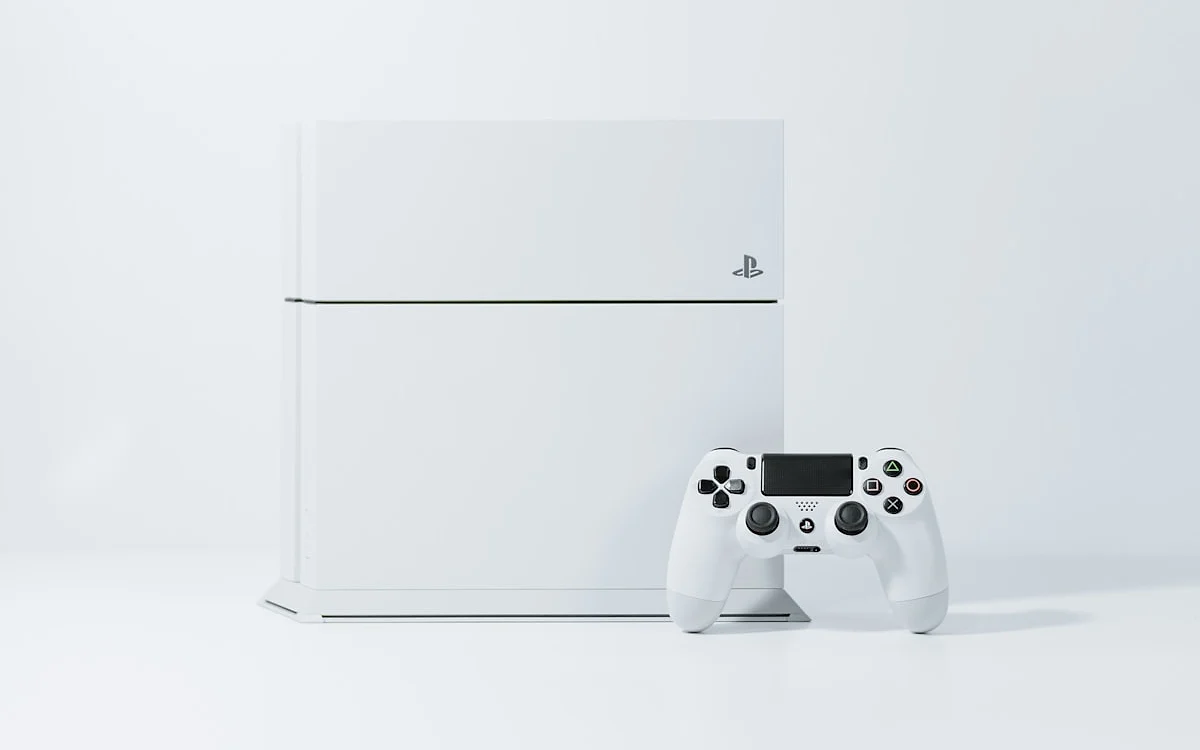 Console e controle PlayStation em still de produto Console e controle PlayStation lado a lado em still de produto sobre fundo branco