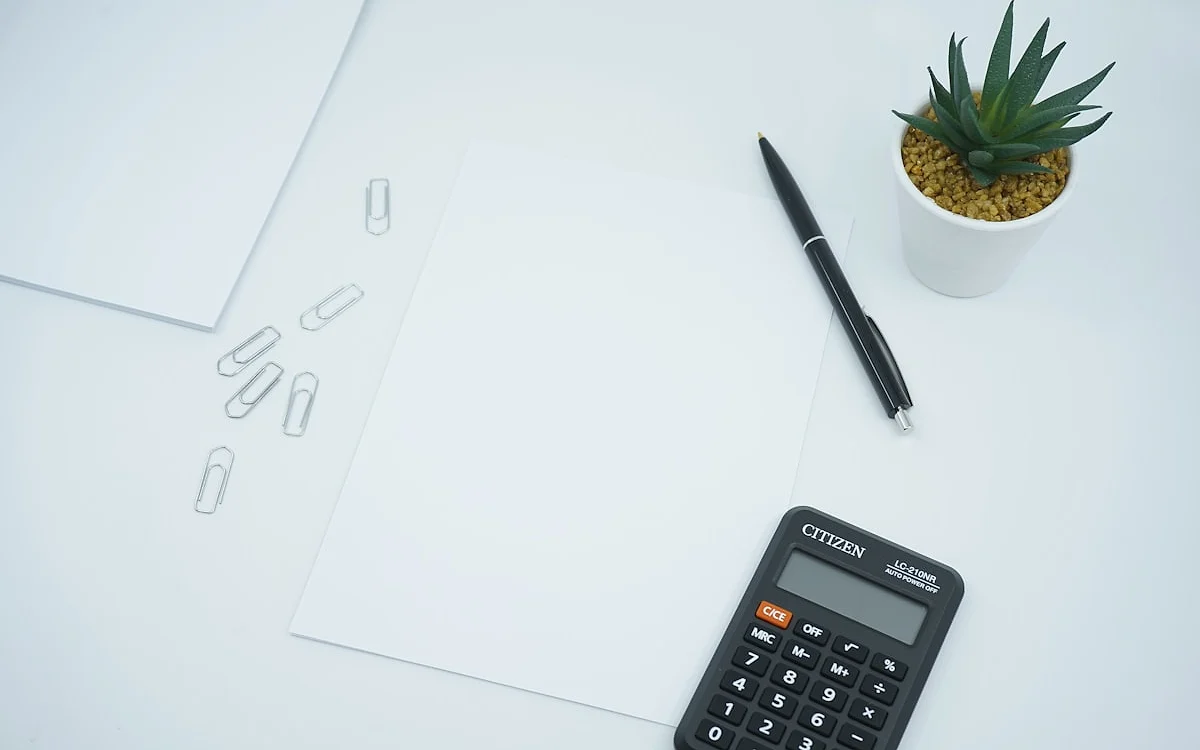 Calculadora sobre notas de dinheiro e um controle de videogame em uma mesa