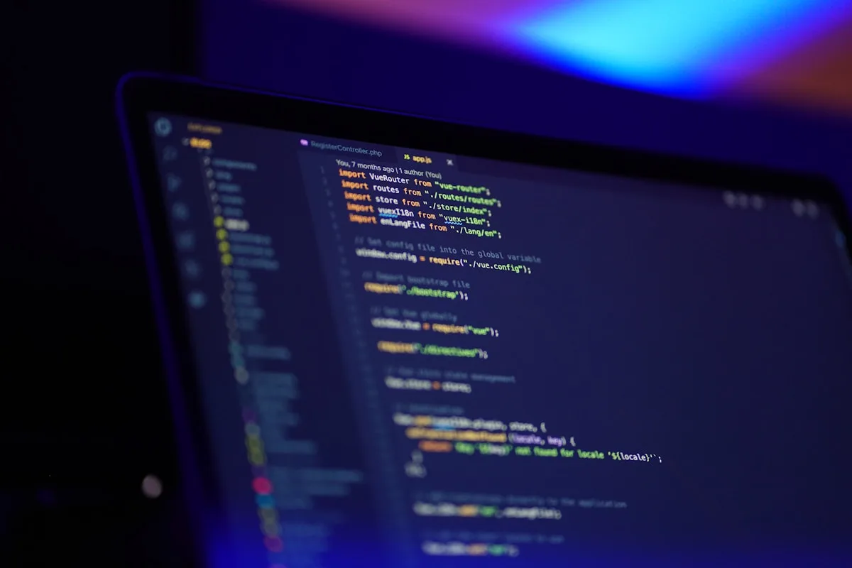 Desenvolvimento de software em ambiente de estúdio Tela de notebook exibindo linhas de código em editor de programação com luz ambiente azul e roxa