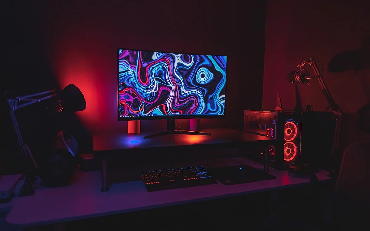 Nobreak conectado a setup gamer com monitor e PC desktop em ambiente escurecido