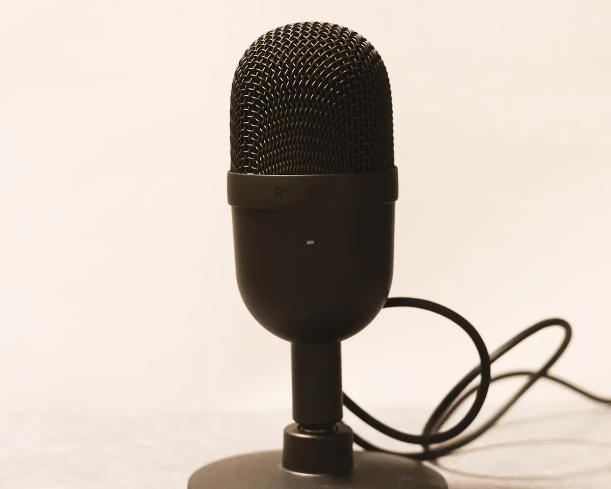 Razer Seiren V2 X visto de frente mostrando grade metálica, corpo cilíndrico e base de suporte articulada