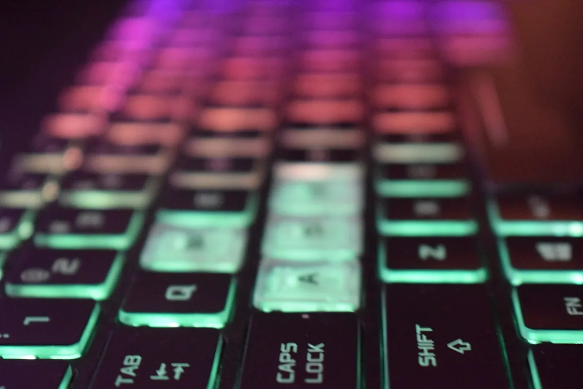 Close das teclas de teclado mecânico 60% com RGB colorido vazando pela base e keycaps double-shot