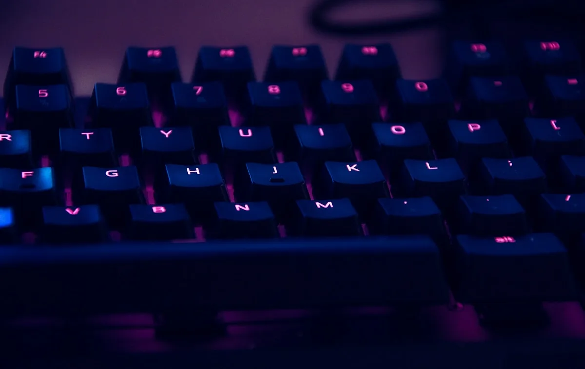 Teclado mecânico TKL compacto de bordas finas ao lado de mouse gamer em mesa escura