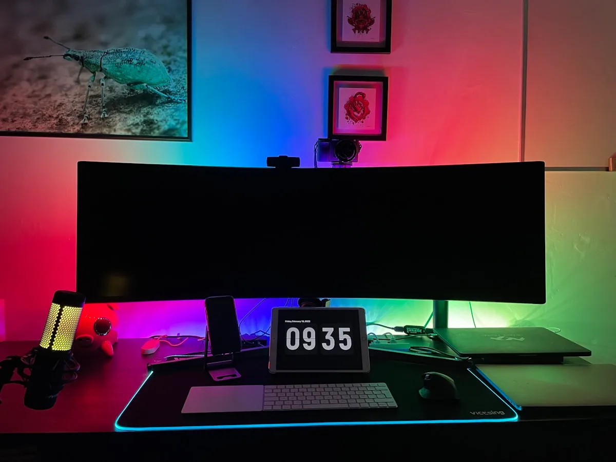Monitor ultrawide com gradiente de cores RGB na parede atrás, típico de fita RGBIC