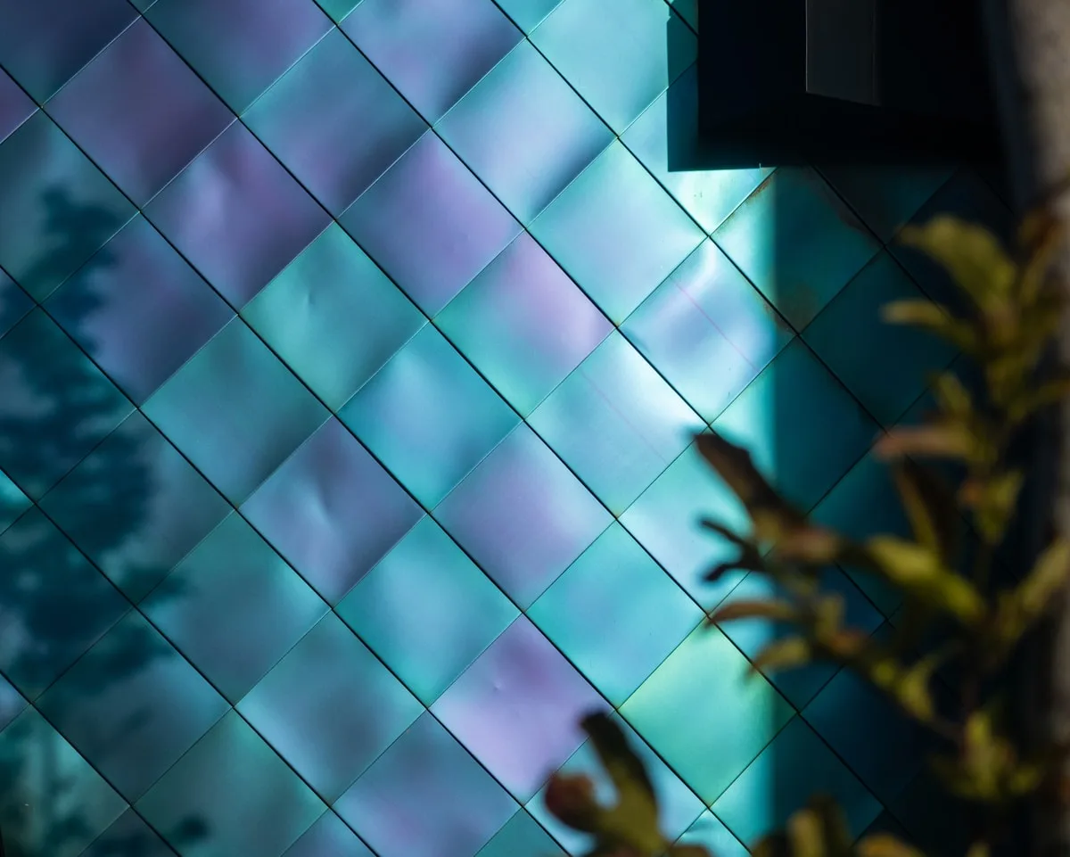 Painéis hexagonais com reflexo em azul e roxo, efeito de camada dupla de luz na parede