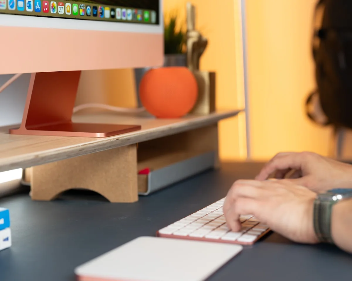 Suporte de mesa simples vs braço articulado Monitor apoiado em suporte de mesa simples sem articulação ao lado de teclado em setup colorido