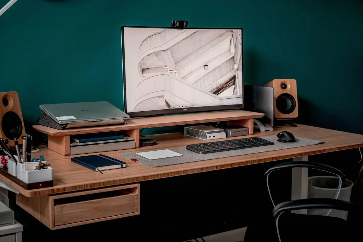 Mesa de escritório organizada com monitor, teclado e caixas de som em setup de home office