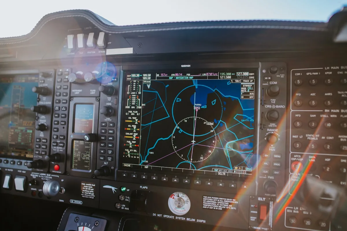 Painel de aviônicos de aeronave com tela de navegação ligada e fileiras de disjuntores ao lado