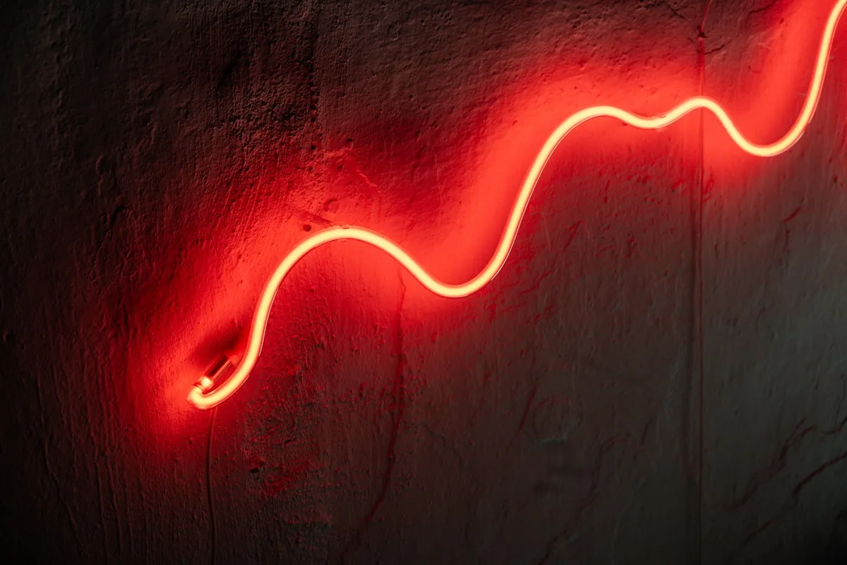 Fita LED RGB decorativa Fita de LED em formato neon vermelho, curvando sobre parede de textura rústica
