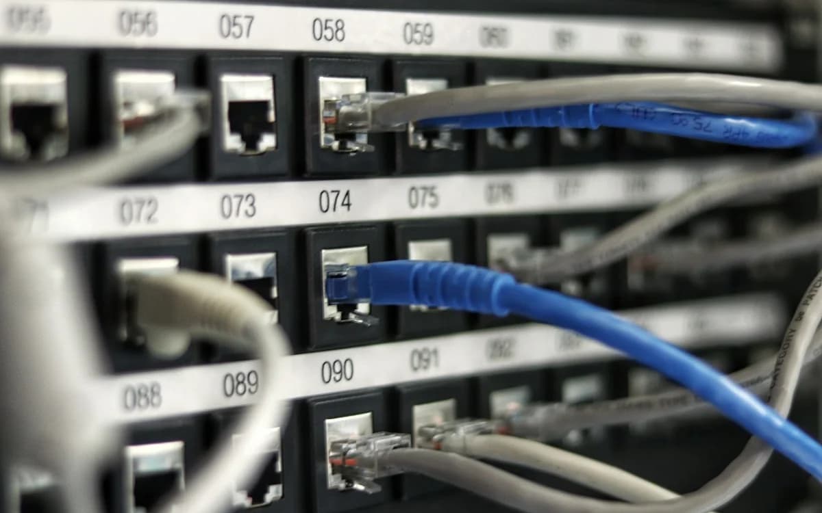 Cabo de rede ou Wi-Fi para jogos: qual escolher Cabo de rede Ethernet conectado a roteador ao lado de notebook em setup gamer