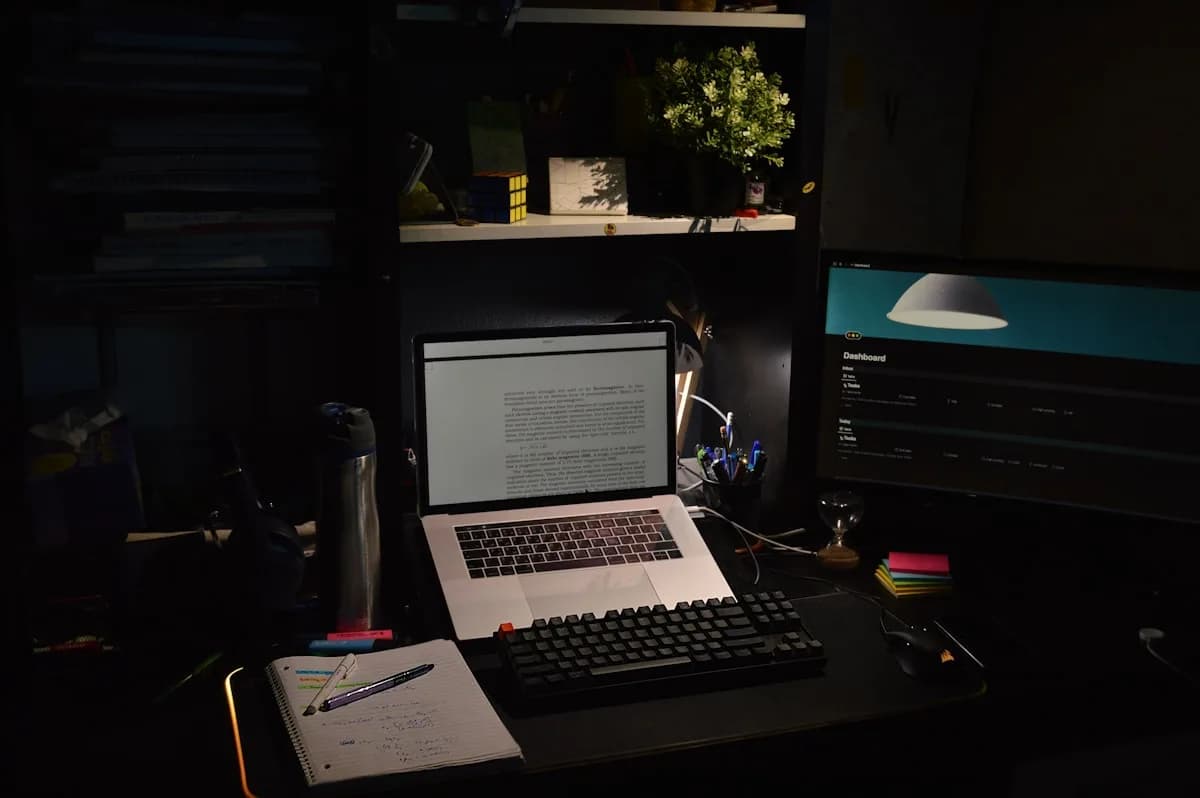 Melhor Fita LED até 100 Reais em 2026 Mesa com notebook, teclado mecânico e monitores em quarto escuro sem iluminação de fundo