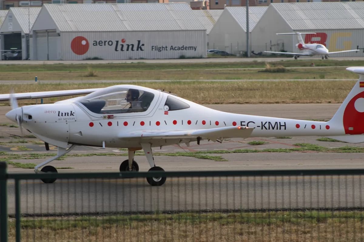 Melhor Joystick para Simulador de Voo em 2026 Avião monomotor de instrução estacionado na pista de um aeroclube, hangares ao fundo