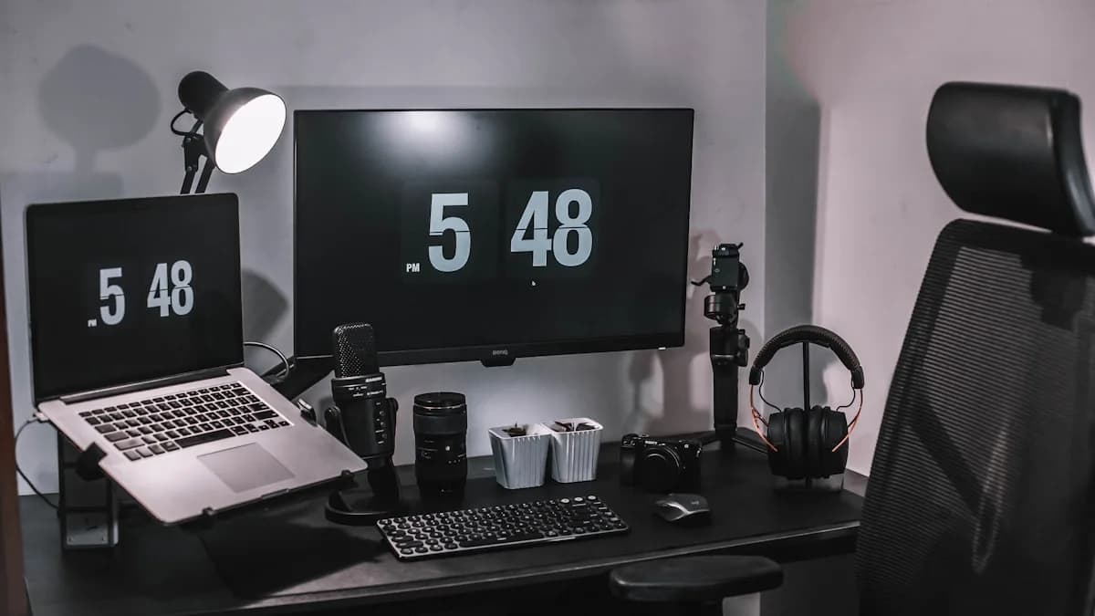Mesa de home office com notebook em suporte elevado, monitor e microfone organizados