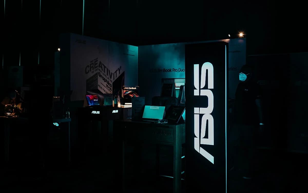 Melhor Mini PC ASUS 2026: ROG NUC e Linha Compacta Estande da ASUS em feira de tecnologia com letreiro iluminado e notebooks expostos