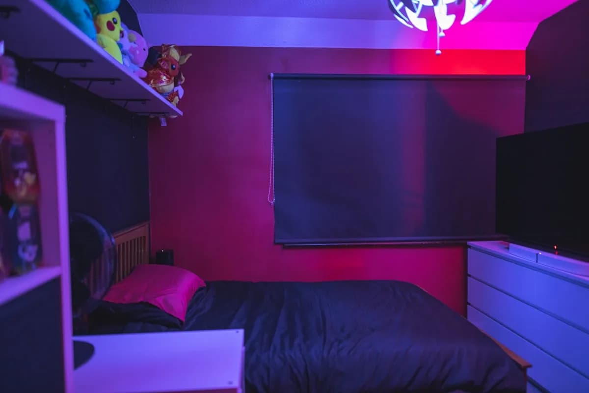Melhor Neon LED para Quarto Gamer em 2026 Quarto gamer com luz ambiente rosa e neon ao fundo da cama durante a noite