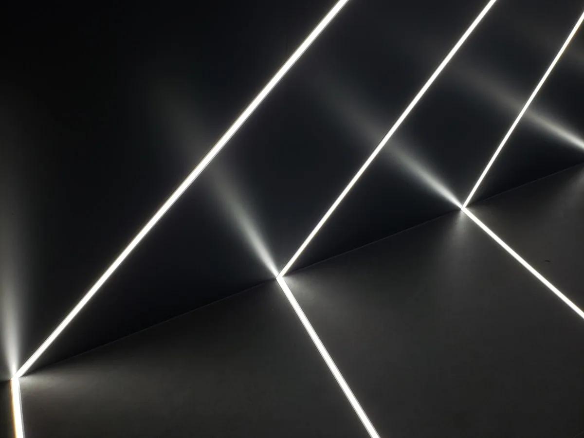 Melhor Painel de Luz Nanoleaf em 2026 Painel de luz triangular formando linhas brancas que convergem em ponta na parede escura