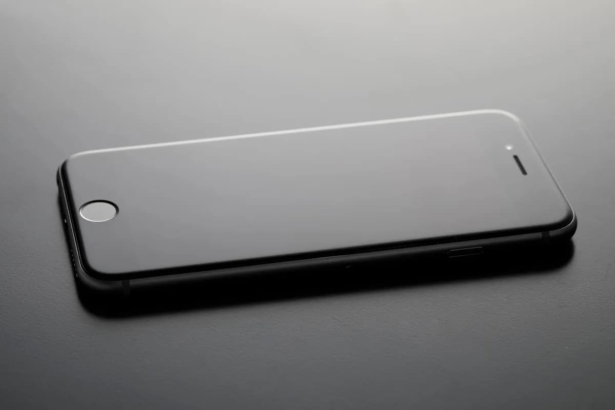 Melhor Película para ROG Ally: 5 Opções em 2026 Smartphone preto com a borda da proteção de tela refletindo luz, contexto de película para PC portátil gamer