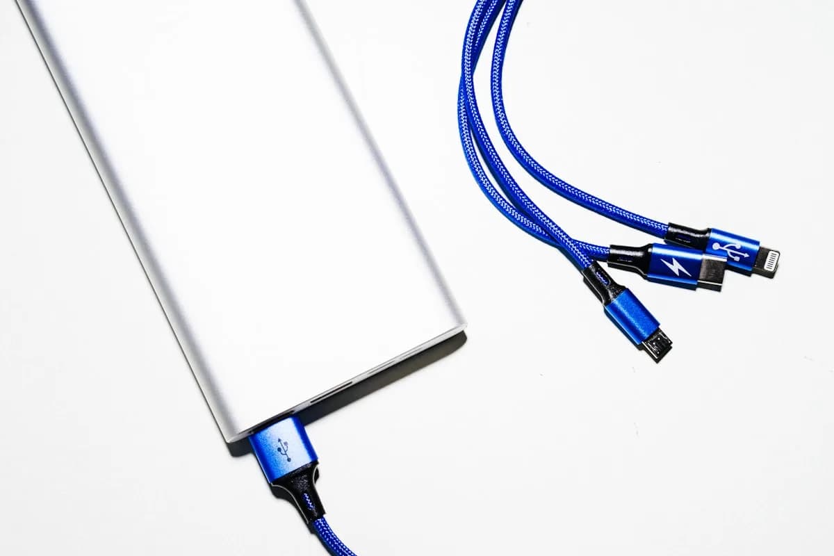 Melhor Power Bank para Steam Deck: Top 5 em 2026 Power bank branco ao lado de cabos USB-C trançados em azul sobre fundo claro