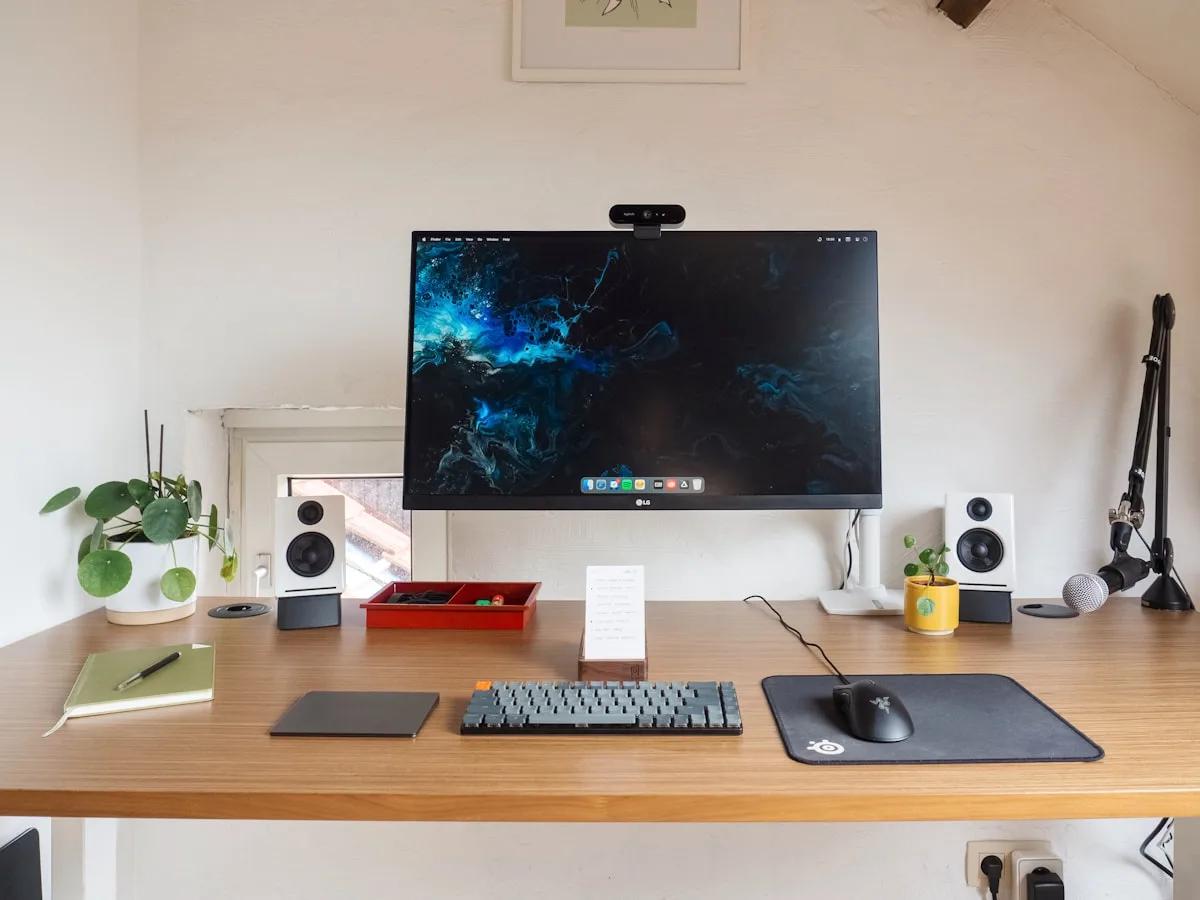 Melhor Suporte de Monitor ELG em 2026 Monitor preso em suporte articulado ELG com webcam sobre mesa de escritório organizada
