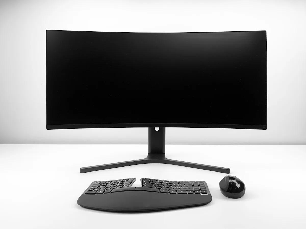 Suporte de Monitor para Ultrawide em 2026 Monitor ultrawide curvo sobre mesa de escritório com braço articulado erguendo a tela