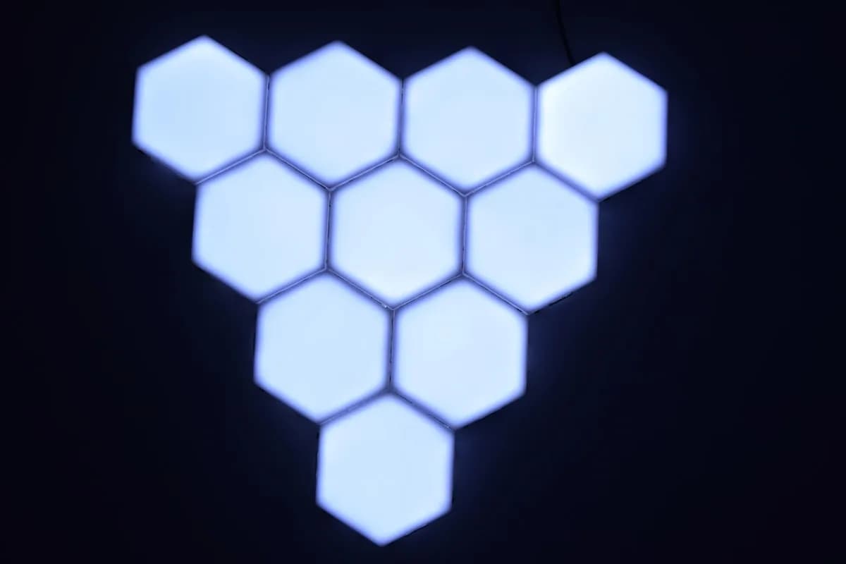 Nanoleaf Shapes Hexagons Review em 2026 Painéis hexagonais brancos montados na parede formando desenho triangular de luz