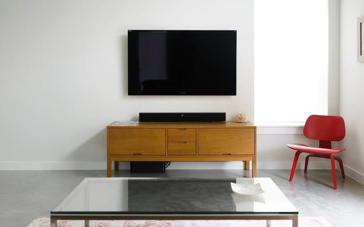 O que é Soundbar? Como Funciona e Quando Vale a Pena (2026) Soundbar posicionada abaixo de uma TV em sala de estar com iluminação ambiente