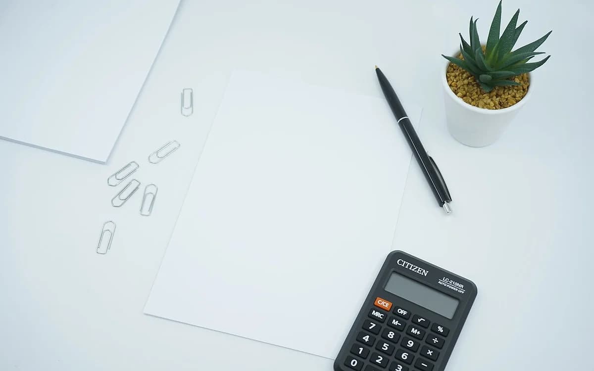 Calculando o custo total de jogar GTA 6 Calculadora sobre notas de dinheiro e um controle de videogame em uma mesa