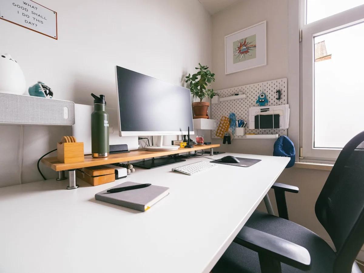 Suporte de Monitor Simples ou Duplo: Qual Escolher em 2026 Mesa de home office com monitor único sobre suporte de madeira e cadeira ergonômica ao fundo