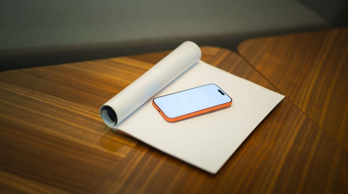 Smartphone em mesa de madeira para escolha de celular Smartphone sobre papel enrolado em uma mesa de madeira, representando escolha de celular