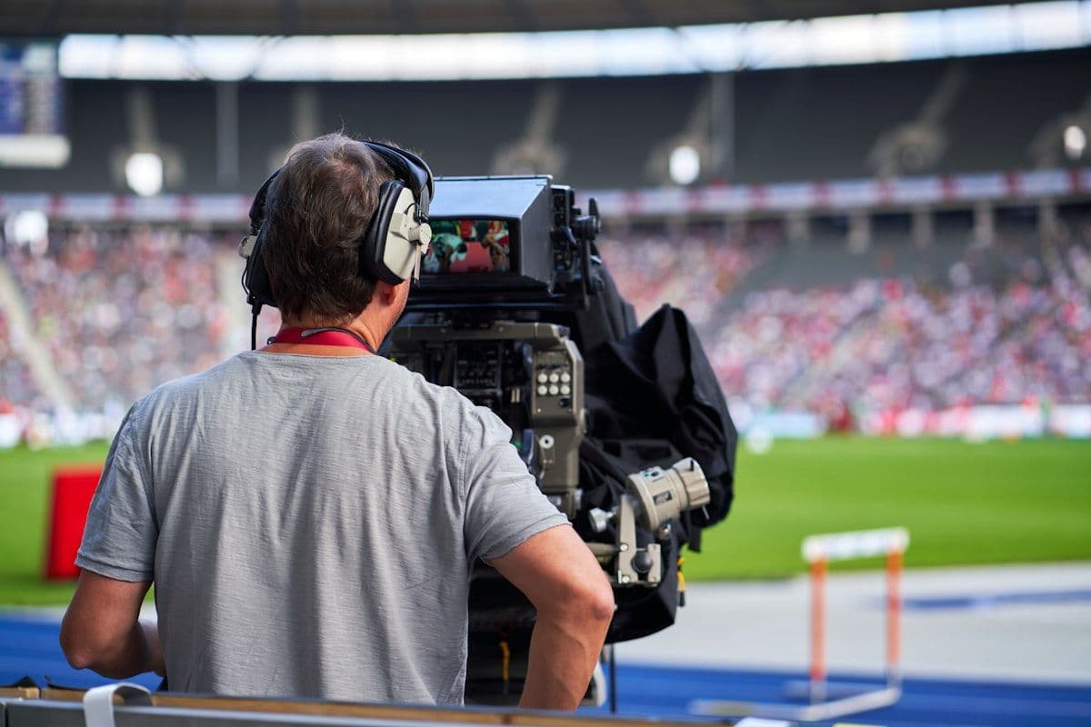 Transmissão ao vivo de futebol na TV: jogos de hoje Transmissão ao vivo de jogo de futebol na TV, com torcedores animados assistindo.