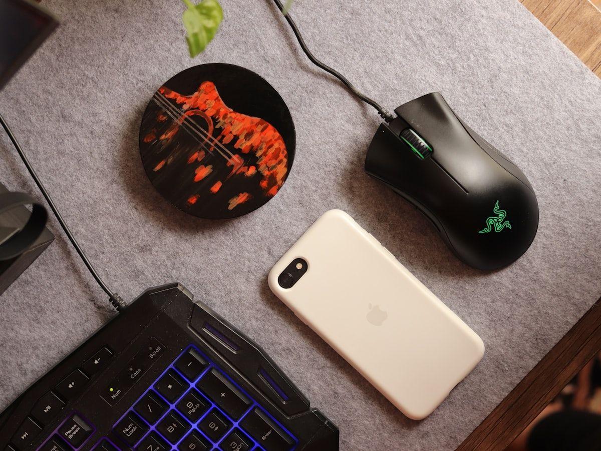 Setup gamer completo: teclado, mouse e celular na mesa Mesa com teclado, mouse, celular e mouse pad, ideal para setup gamer mobile.