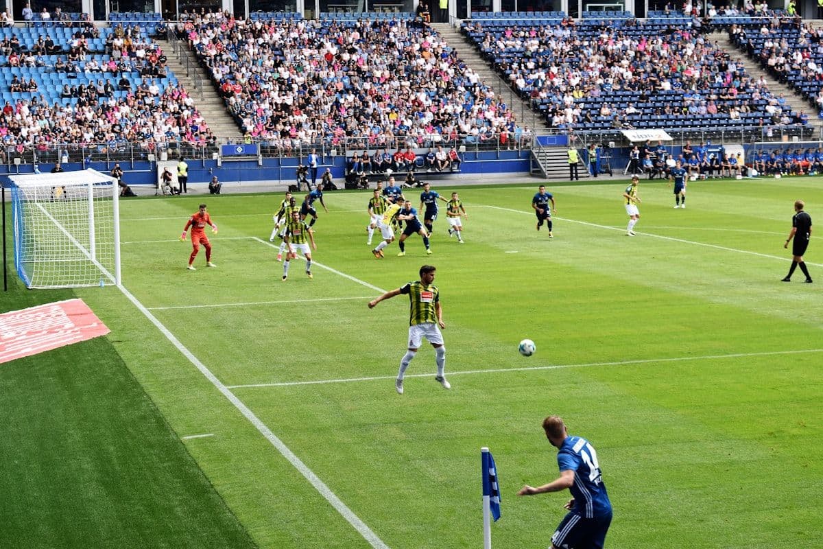 Jogadores em ação no campo de futebol sob o sol Jogadores de futebol em campo durante o dia, disputando uma partida emocionante