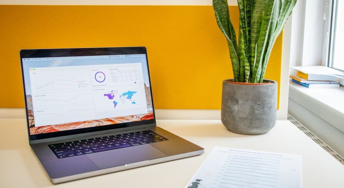 Notebook em mesa com planta, ideal para trabalho produtivo Notebook sobre uma mesa ao lado de uma planta verde, ideal para trabalho