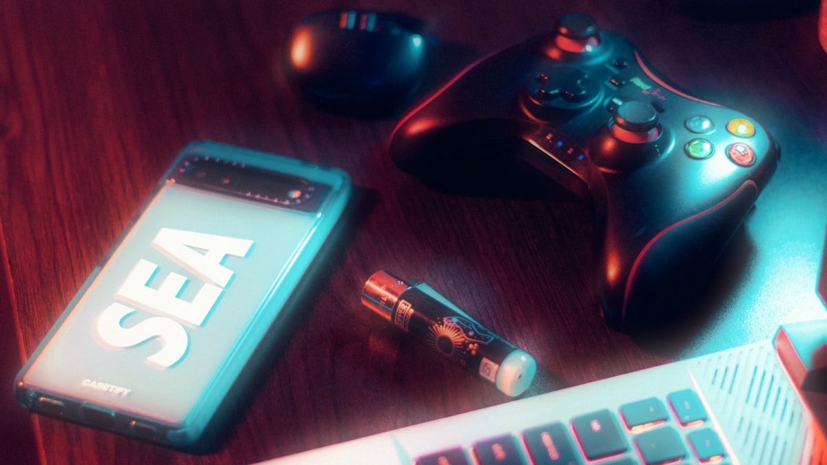 Celular, caneta e controle: tecnologia em jogos Celular, caneta e controle de videogame sobre uma mesa, representando tecnologia e jogos