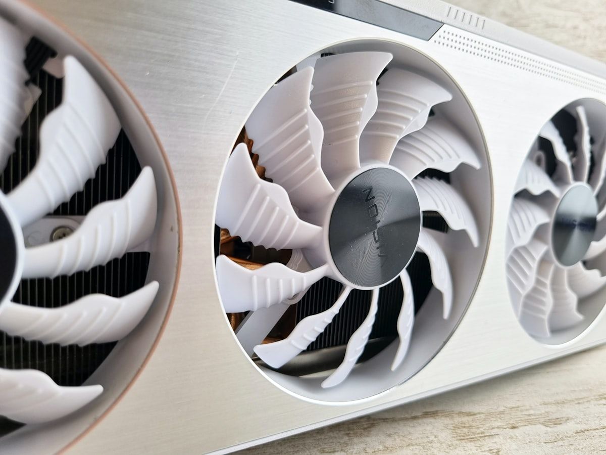 Detalhe de coolers em superfície metálica para RTX 5060 Ti Close-up de dois coolers em uma superfície metálica, destacando a eficiência de refrigeração para a RTX 5060 Ti