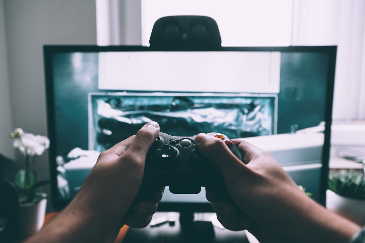 Jogador com controle assistindo The Last of Us 3 na TV Pessoa segurando controle de videogame em frente à televisão assistindo The Last of Us 3