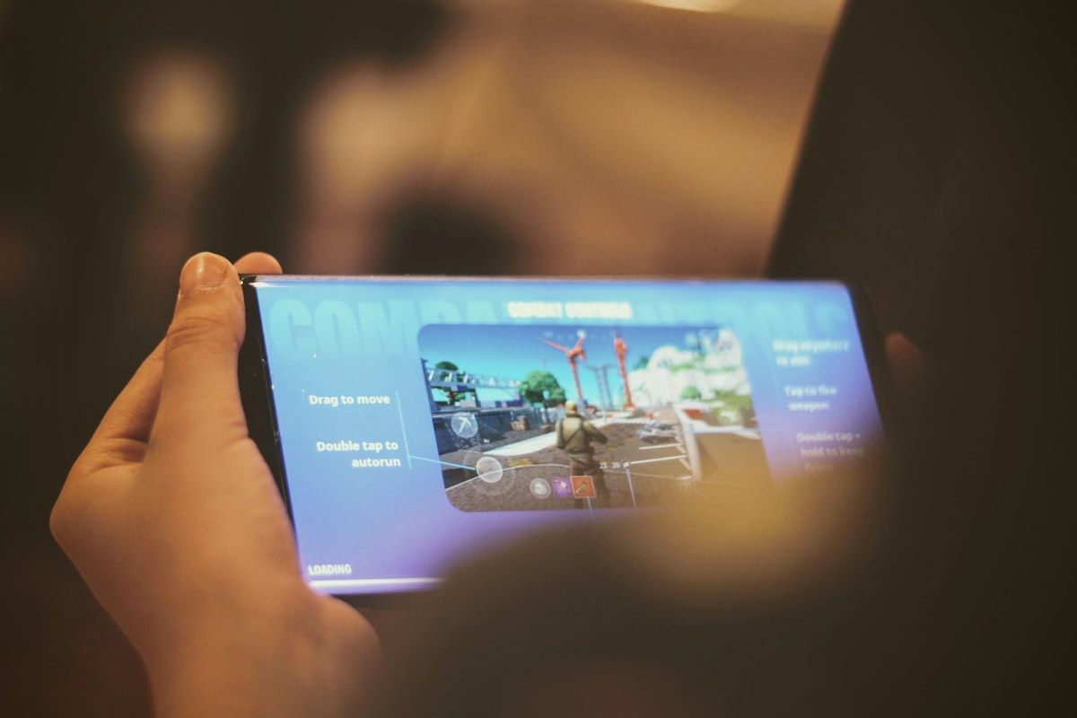 Pessoa segurando um smartphone Android preto enquanto joga Fortnite Mobile em 2026