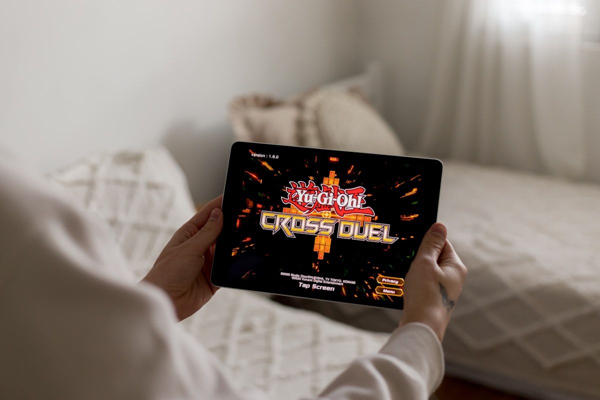 Pessoa segurando um tablet com um jogo de vídeo game em tela, jogando e se divertindo.