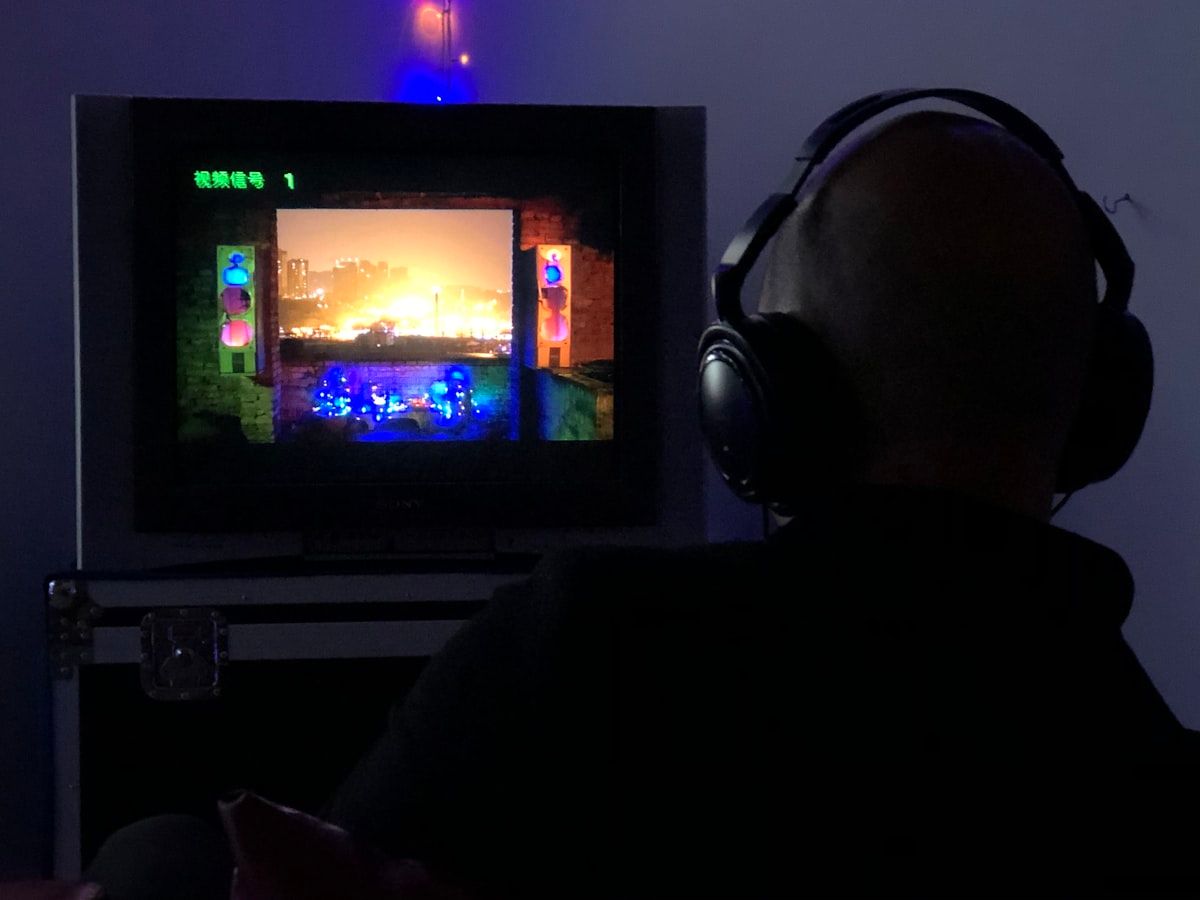 Homem jogando CS2 com fones de ouvido e TV ligada Homem sentado em frente à TV usando fones de ouvido, jogando CS2