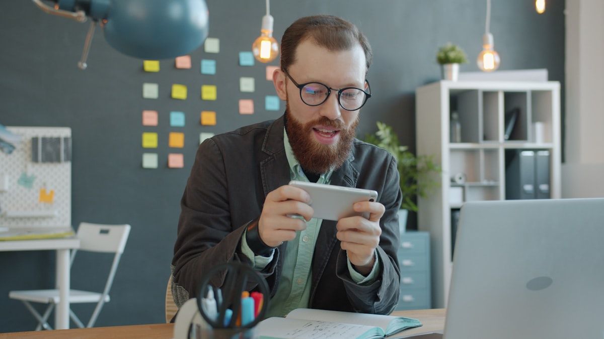 Homem jogando jogos de construção no smartphone Homem jogando em smartphone na mesa, explorando jogos de construção.