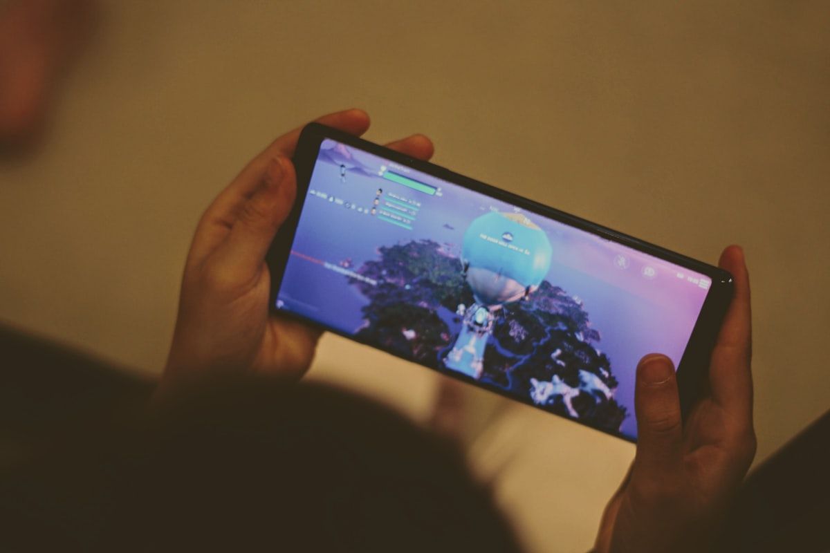 Pessoa segurando smartphone Android preto enquanto joga Fortnite Mobile