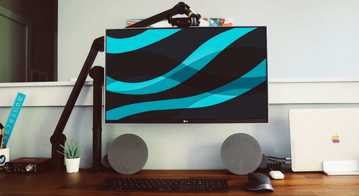 Monitor PC Gamer com Alto-falantes Cinzas ao Lado Monitor de tela plana ao lado de uma parede e um par de alto-falantes cinzas, ideal para gamers.