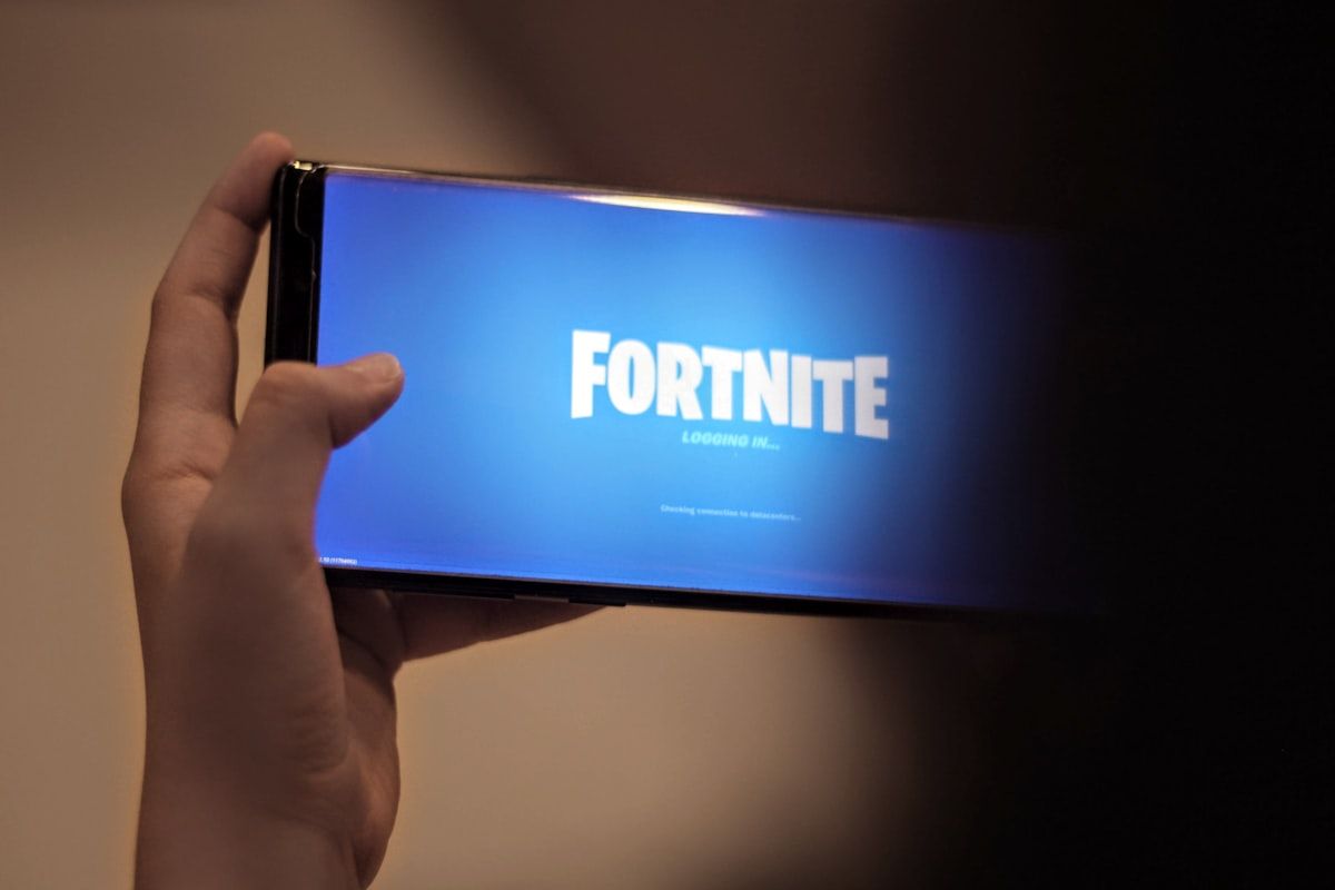Pessoa segurando uma caixa azul e branca relacionada ao Fortnite Mobile 2026
