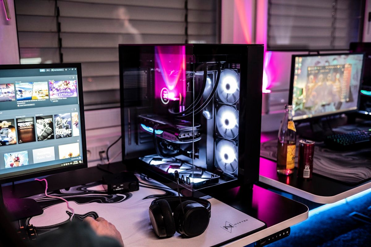 Homem com três monitores em configuração de PC gamer Homem sentado em uma mesa com três monitores de computador, configurando seu PC gamer